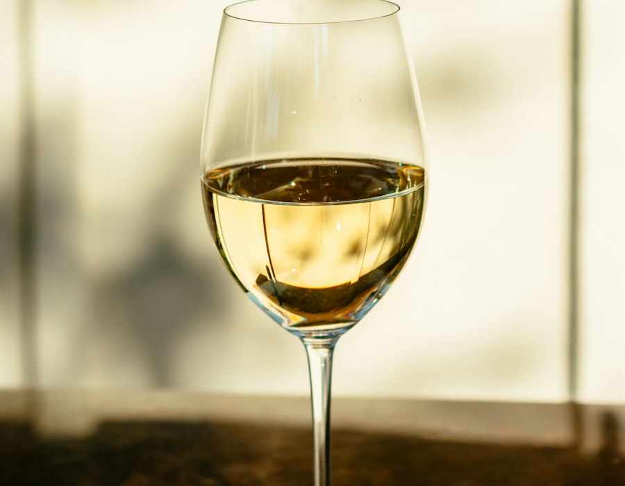 Taça com vinho branco em mesa de madeira